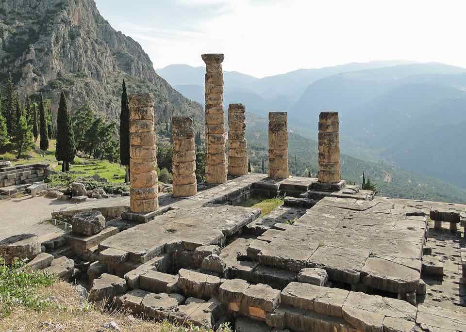 Remaining columns of the Temple of Apollo at Delphi against a mountain slope.